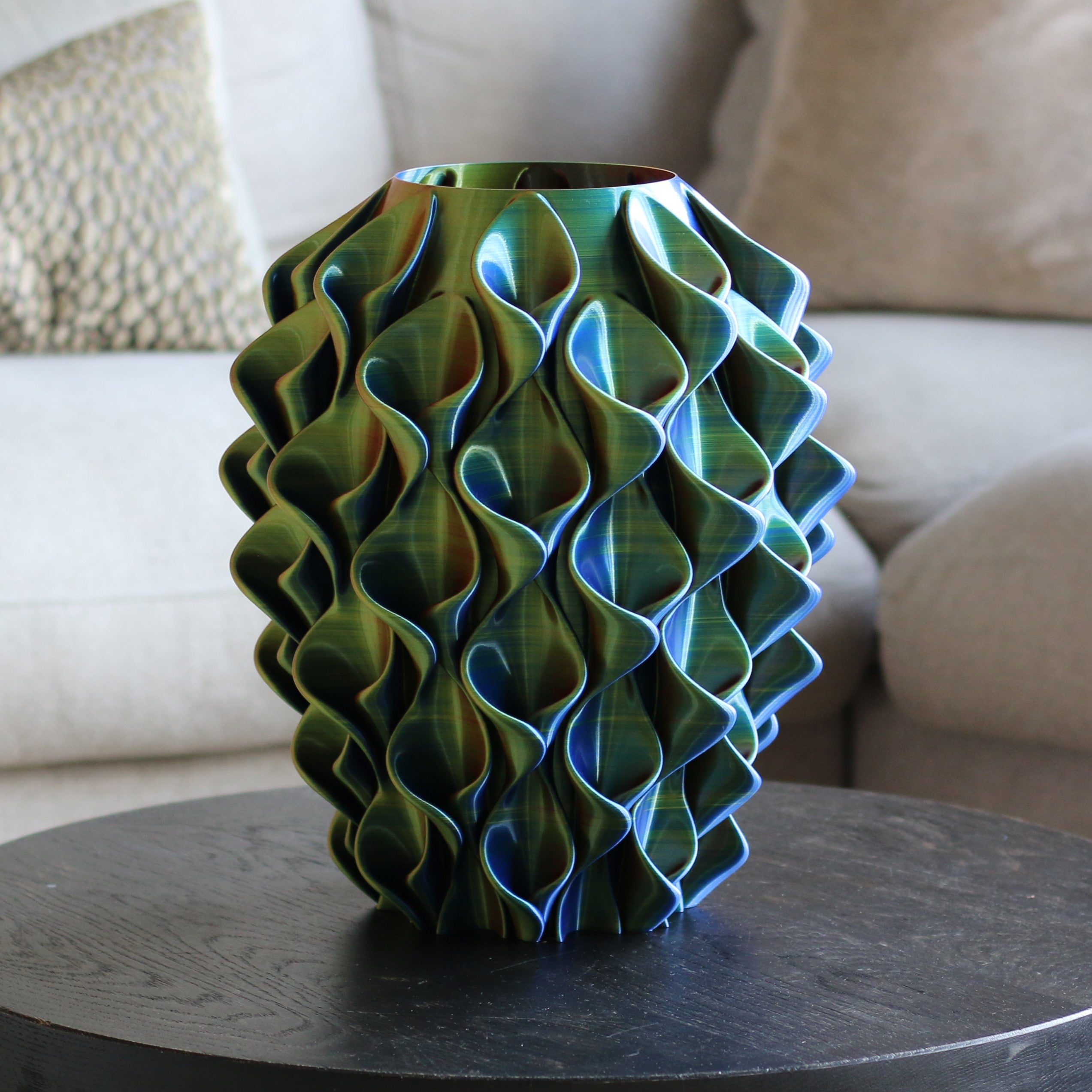 Meerkleurige coral vaas in geel, blauw en rood op een donkere bijzettafel in een woonkamer – 3D-geprinte designvaas met kleurverloop van Studio VormVezel