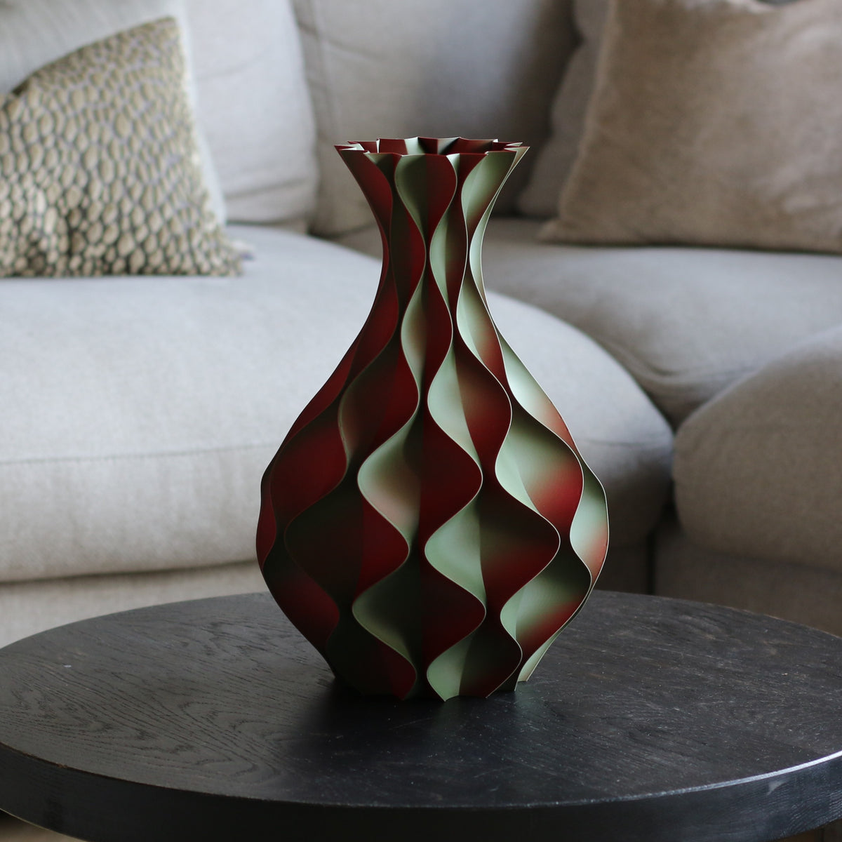Zwart-rood-groene schelp vaas op een zwarte bijzettafel in een woonkamer – sculptuurvaas met golvend kleurverloop van Studio VormVezel