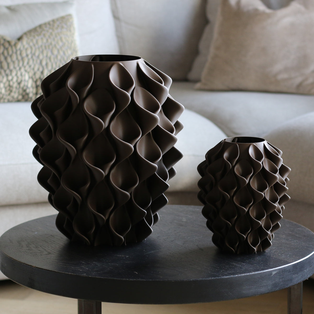 Twee chocoladebruine coral vazen in verschillende maten op een donkere bijzettafel – 3D-geprinte designvazen met coralpatroon van Studio VormVezel