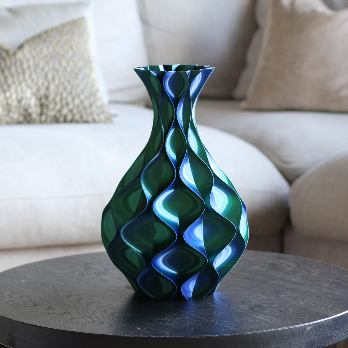 Groen-blauwe schelp vaas op een donkere bijzettafel in een woonkamer – 3D-geprinte designvaas met schelppatroon en metallic glans van Studio VormVezel