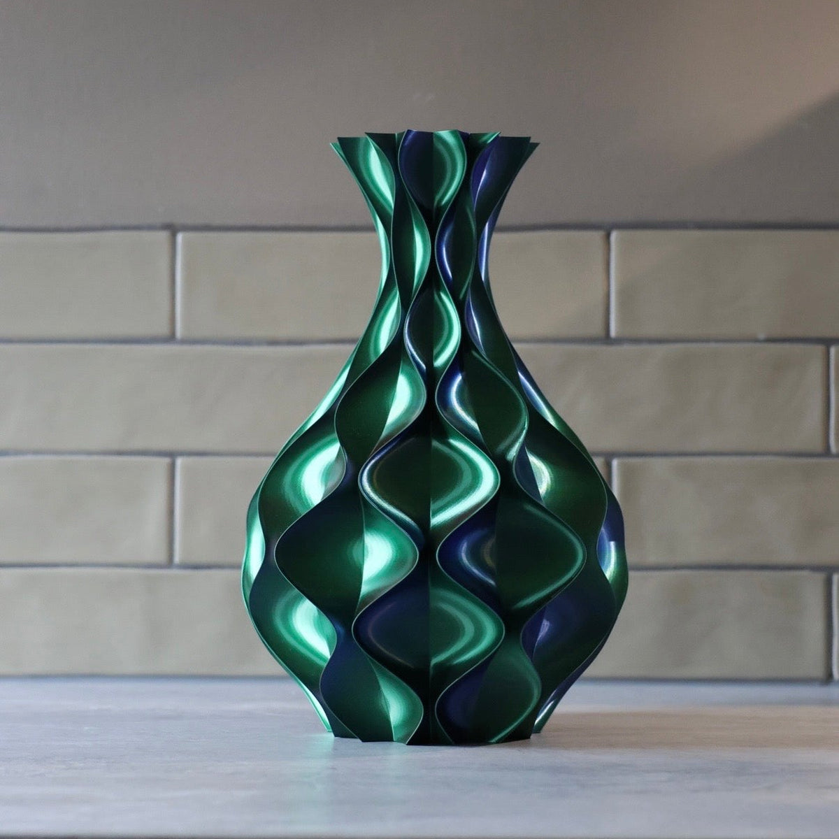 Groen-blauwe schelp vaas voor een stenen tegelmuur – 3D-geprinte sculptuurvaas met golvend schelppatroon en metallic kleurverloop van Studio VormVezel