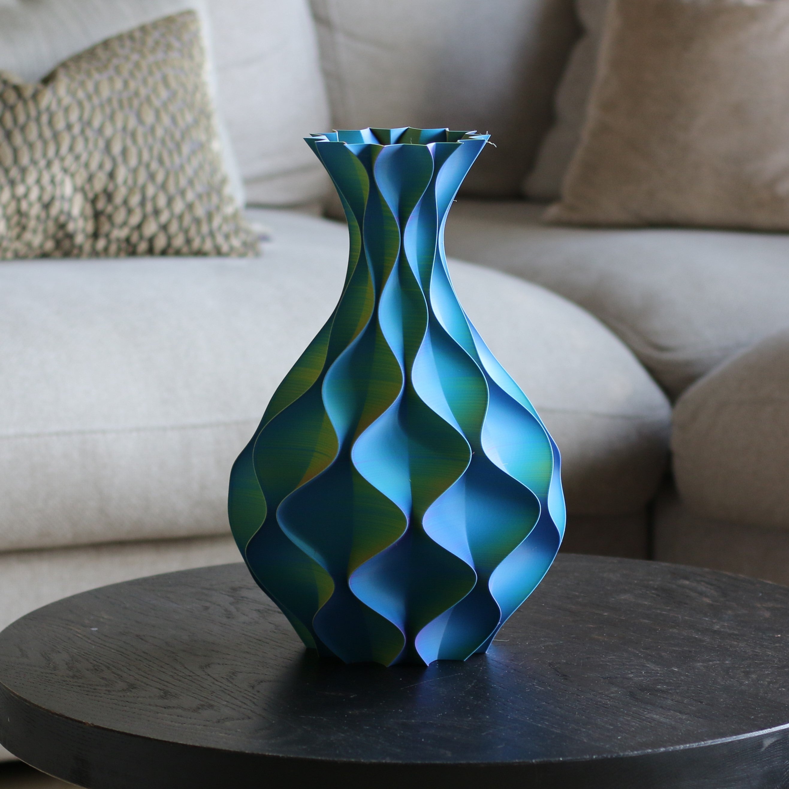 Blauw-groene schelp vaas op een zwarte bijzettafel voor een bank – slanke 3D-geprinte designvaas van Studio VormVezel