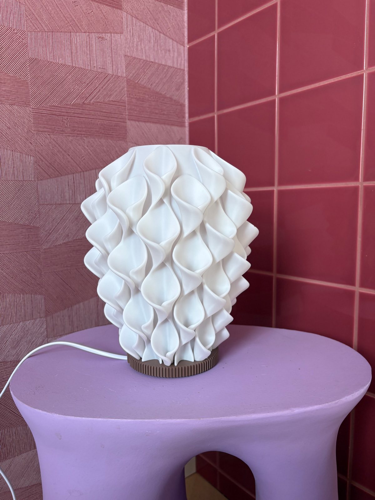 Coral tafellamp uit, gebroken wit met golvend reliëf, op een lila bijzettafel voor roze tegels