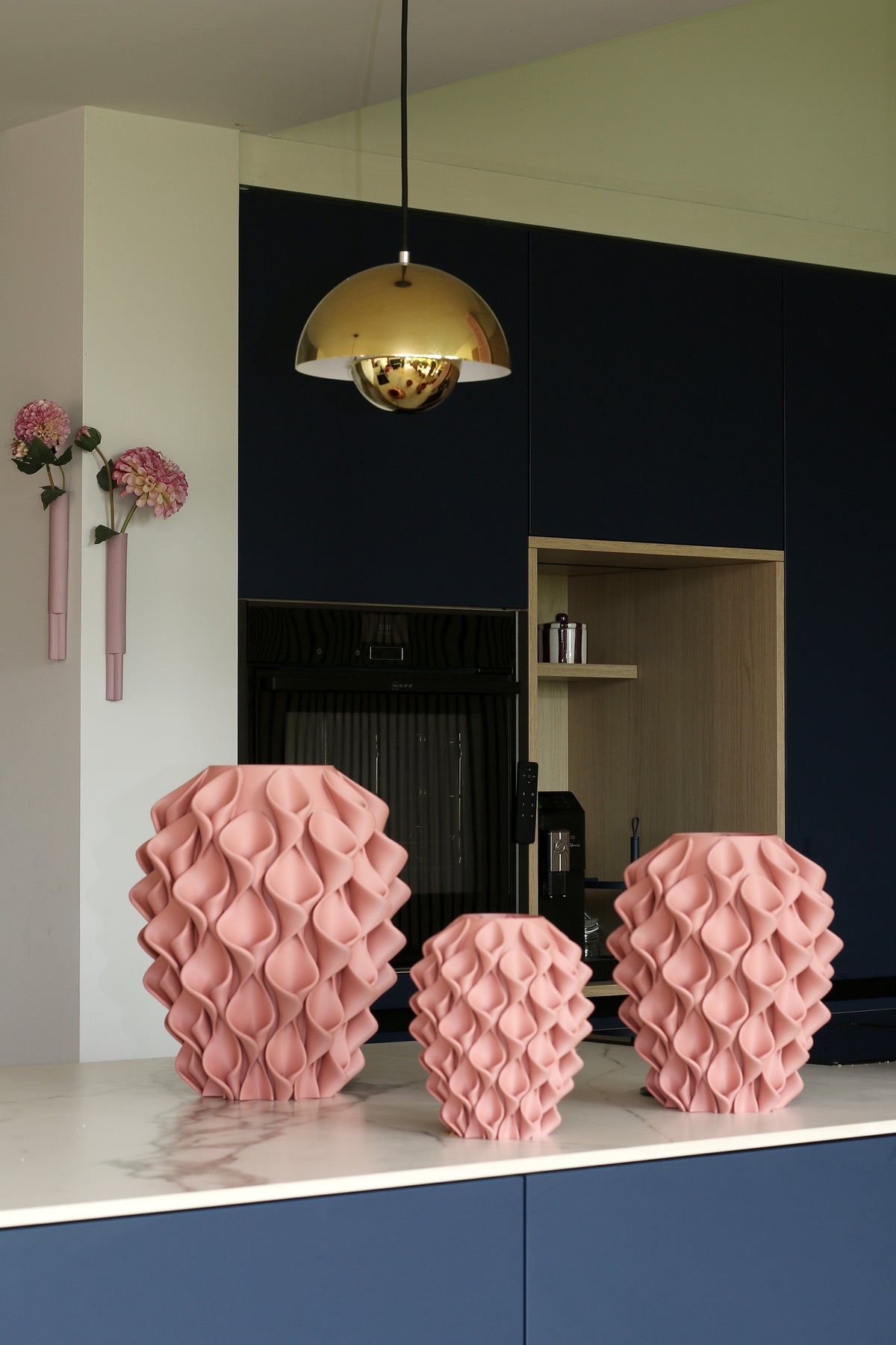 Drie Coral-vazen Oud Roze in verschillende maten op een marmeren keukenblad voor een donkerblauwe keuken